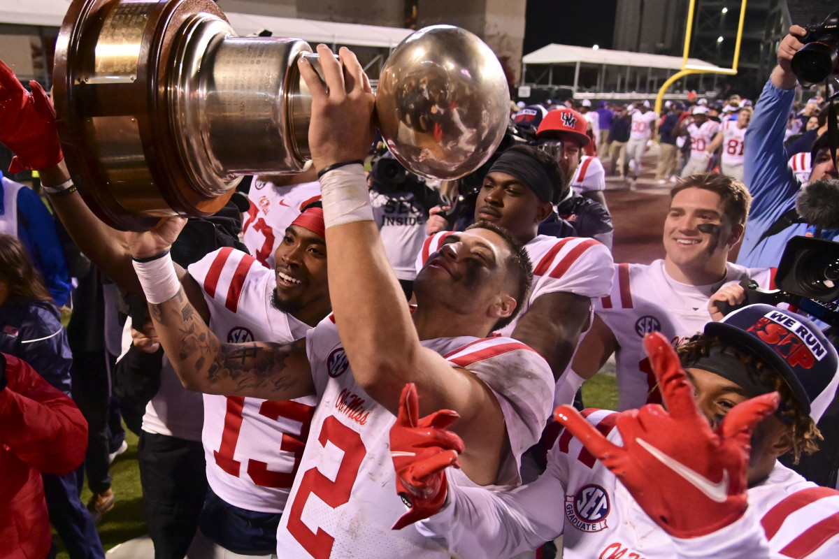 Nov 25, 2021; Starkville, Mississippi, USA; Mississippi Rebels quarterback Matt Corral (2) hoist the Egg Bowl trophy after the game against the Mississippi State Bulldogs at Davis Wade Stadium at Scott Field. Mandatory Credit: Matt Bush-USA TODAY Sports